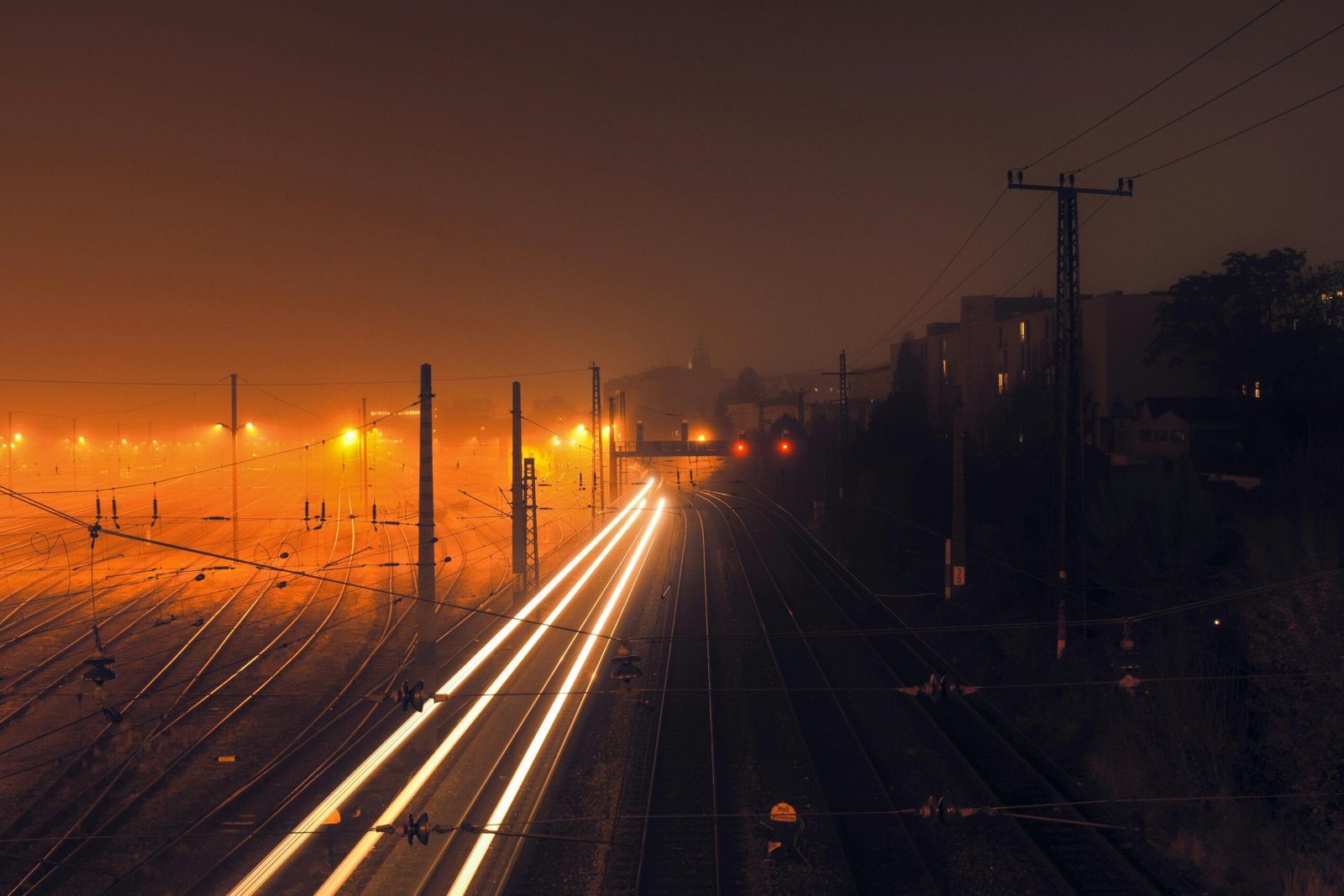 Long exposure photo of a foggy railway at night in Vienna with vibrant light trails.